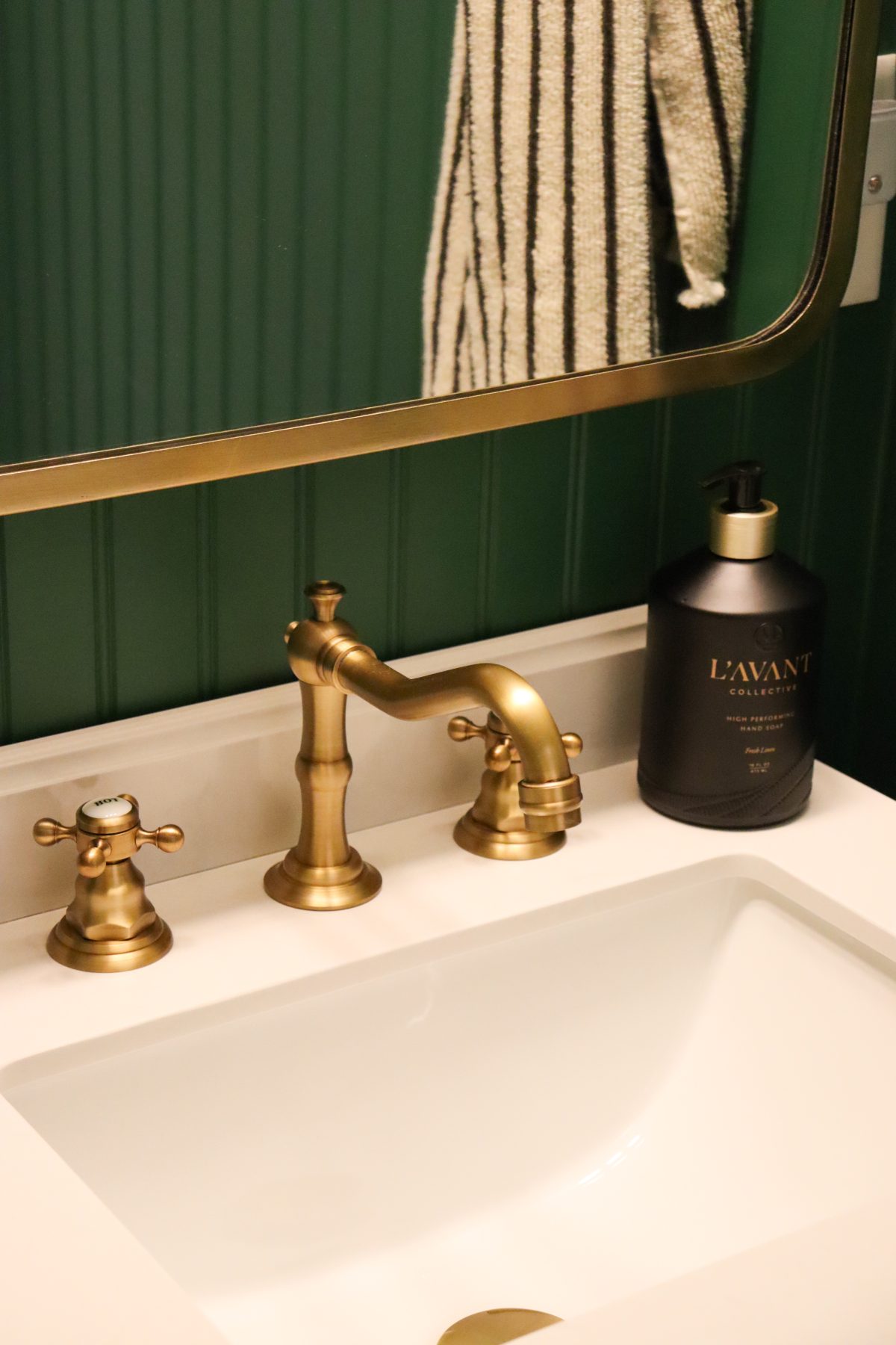 green powder room sink with gold hardware and lavant hand soap